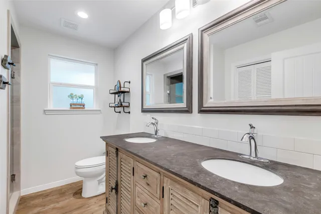 a bathroom with a granite countertop toilet sink and mirror