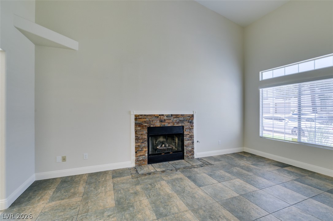 200 Luninborg Street Henderson, NV 89074 - Photo 17 of 40 A well-lit room with high ceilings, featuring a stacked stone fireplace and tiled flooring.