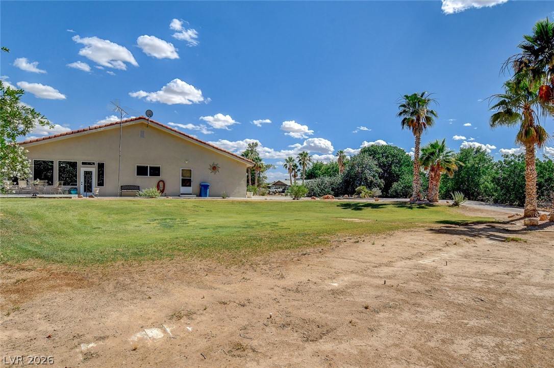 1950 Bowman Road Logandale, NV 89021 - Photo 57 of 81 Palm trees punctuate the verdant lawn leading to this inviting stucco home, set against a bright desert sky.