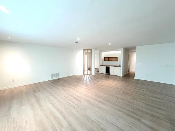 a view of a kitchen and an empty room with wooden floor
