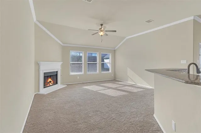 a view of a livingroom with a fireplace ceiling fan and windows