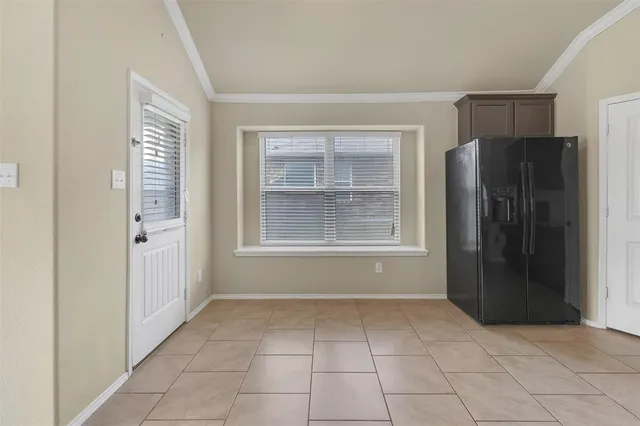 a view of an empty room with window and refrigerator