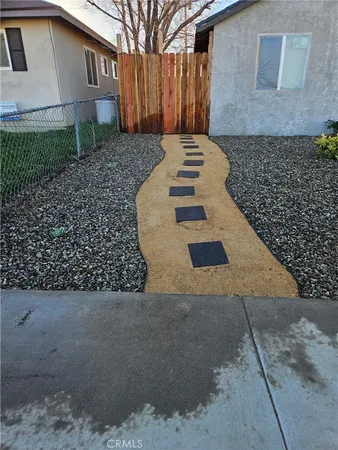 a view of a backyard with plants and large tree