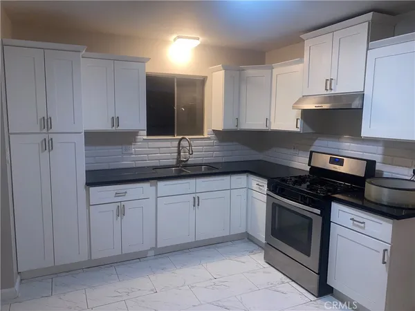 a kitchen with granite countertop white cabinets and stainless steel appliances