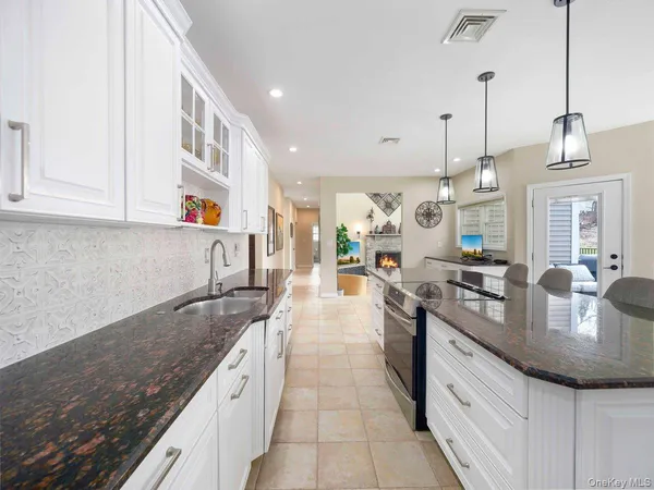 a large kitchen with granite countertop a sink a stove and cabinets