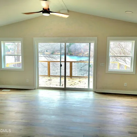 a view of an empty room with window and wooden floor