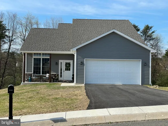 a front view of house with yard and trees in the background