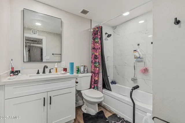 a bathroom with a sink vanity mirror bathtub and toilet