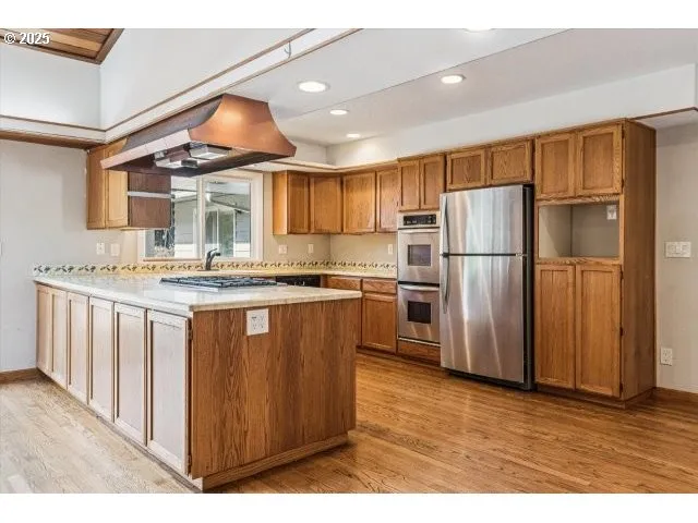 a kitchen with stainless steel appliances granite countertop a refrigerator a sink dishwasher a oven with white cabinets and wooden floor