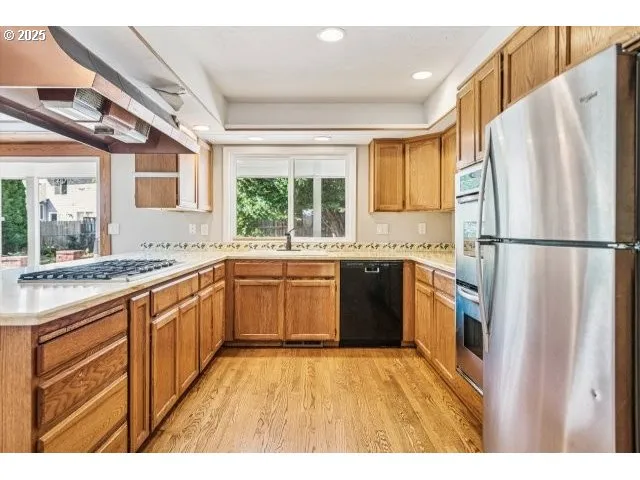 a kitchen with stainless steel appliances granite countertop a refrigerator a sink dishwasher a stove with large countertops and cabinets