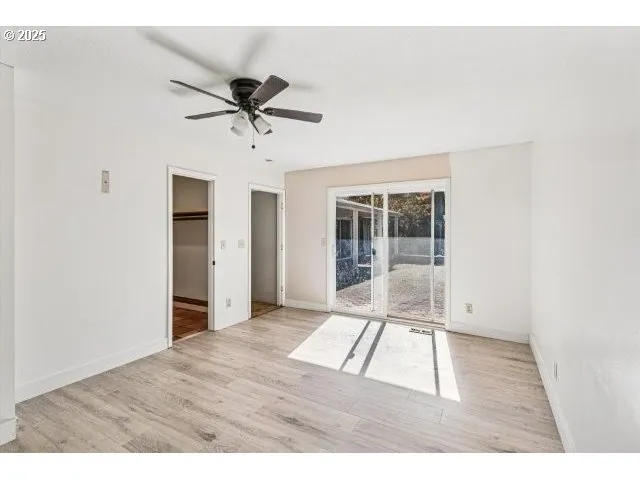 a view interior of a house with wooden floor a ceiling fan and windows