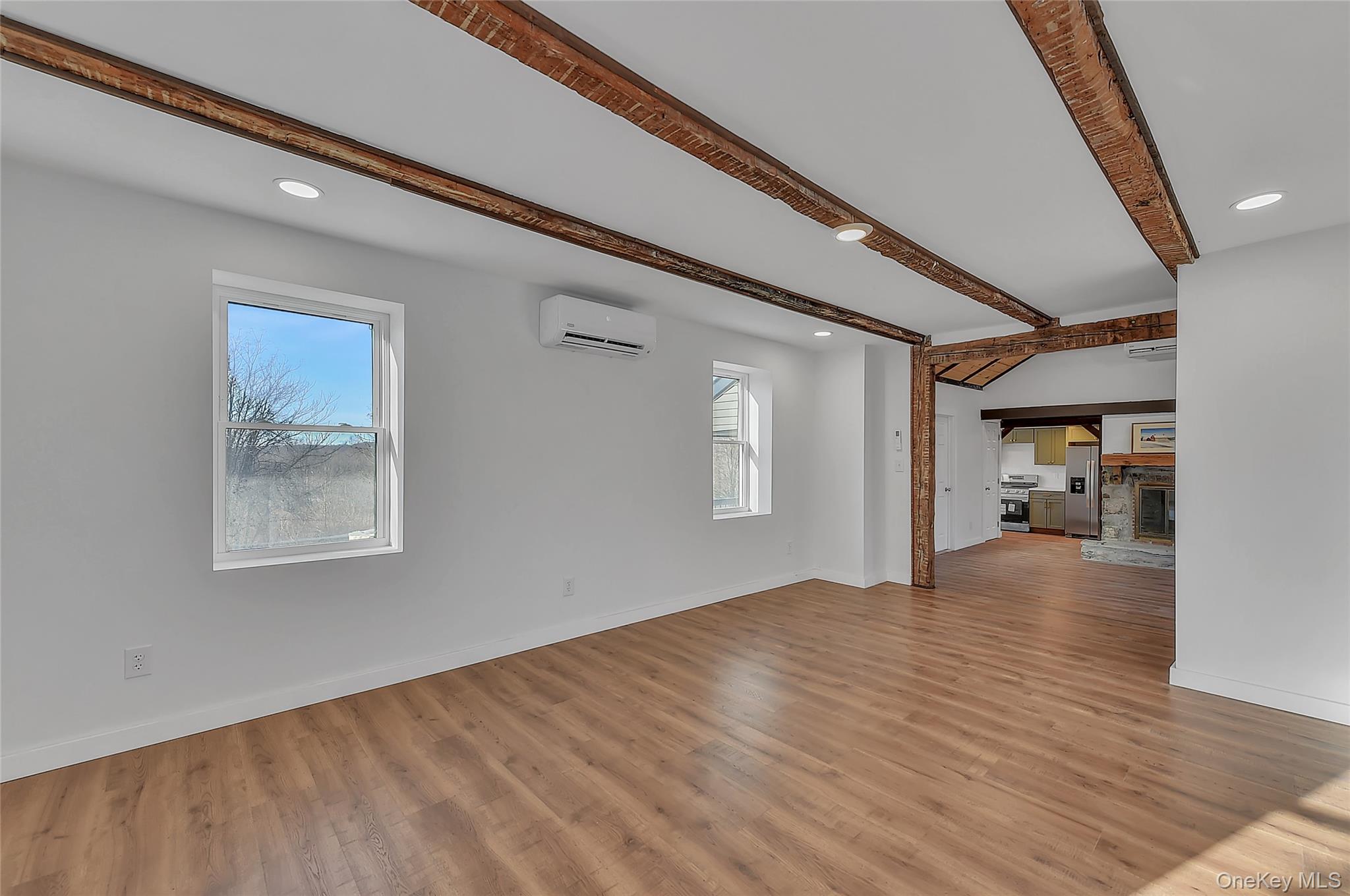 67 Jacobs Road Westtown, NY 10998 - Photo 15 of 35 Unfurnished living room featuring recessed lighting, a stone fireplace, beam ceiling, light wood-style flooring, and a wall unit AC