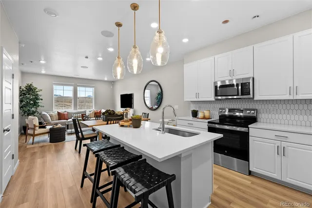 a kitchen with stainless steel appliances a dining table chairs stove refrigerator and cabinets