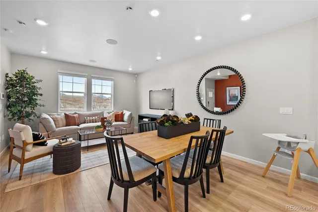 a view of a dining room with furniture a kitchen and wooden floor