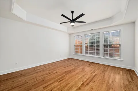 a view of empty room with wooden floor and fan