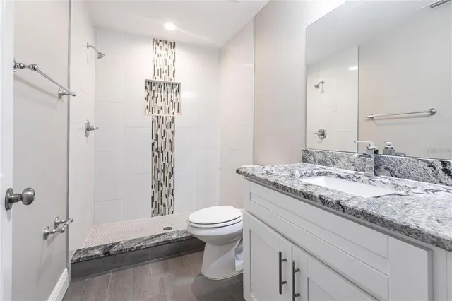 a bathroom with a granite countertop sink toilet and shower