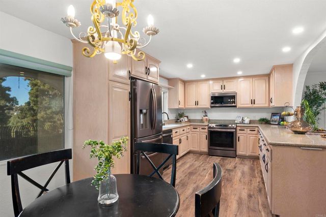 a kitchen with stainless steel appliances granite countertop a kitchen island and chairs in it