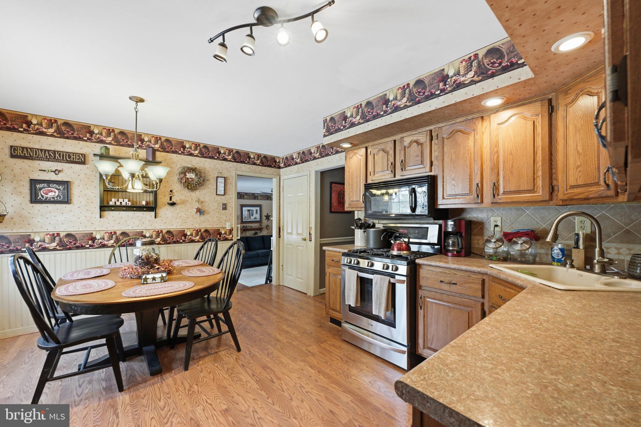 1848 Brackenville Road Hockessin, DE 19707 - Photo 7 of 37 a kitchen with stainless steel appliances granite countertop a stove top oven a sink a dining table and chairs with wooden floor