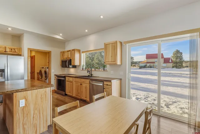 a kitchen with stainless steel appliances kitchen island granite countertop a table chairs sink and cabinets