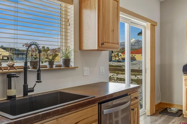 a kitchen with stainless steel appliances kitchen island granite countertop a refrigerator a stove top oven and a sink with wooden floor