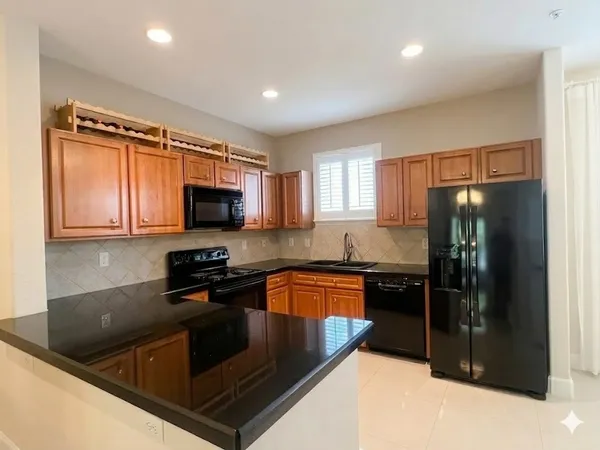 a kitchen with stainless steel appliances granite countertop a refrigerator a sink a stove a microwave and wooden cabinets