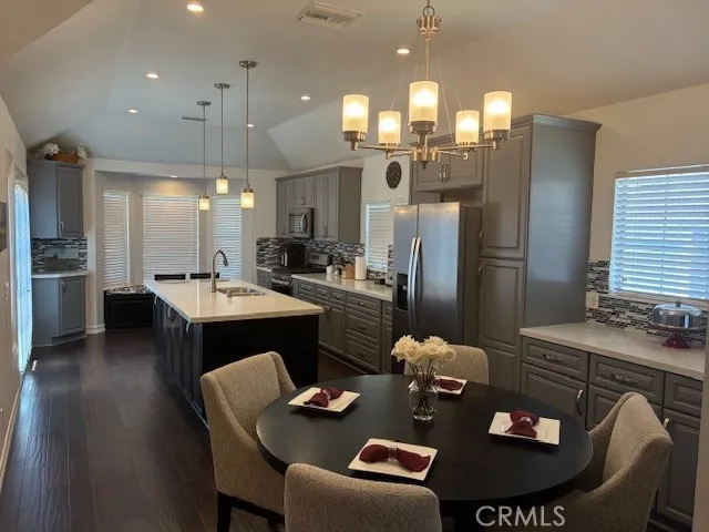 a kitchen with stainless steel appliances granite countertop a refrigerator a sink a stove a dining table and chairs