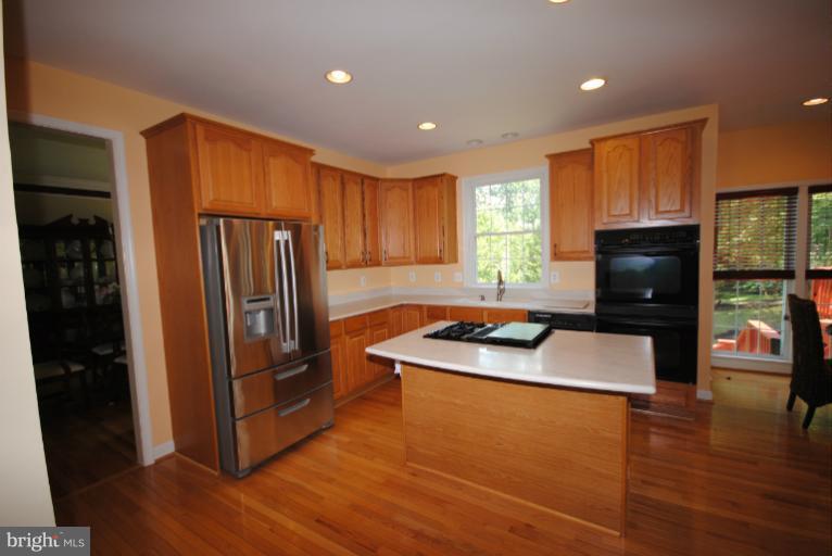 20334 Cliftons Point Street Sterling, VA 20165 - Photo 3 of 30 a kitchen with stainless steel appliances granite countertop a refrigerator a stove top oven a sink and dishwasher with wooden floor