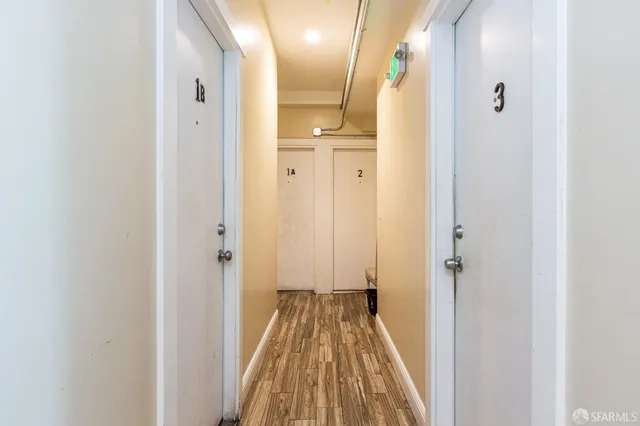 a view of a hallway with wooden floor and a bathroom