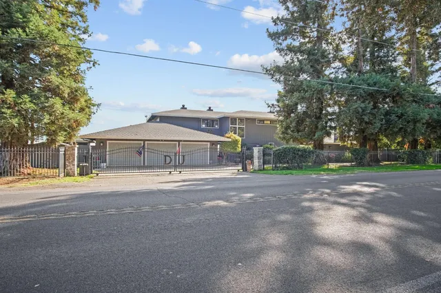 a view of a house with a yard and large trees