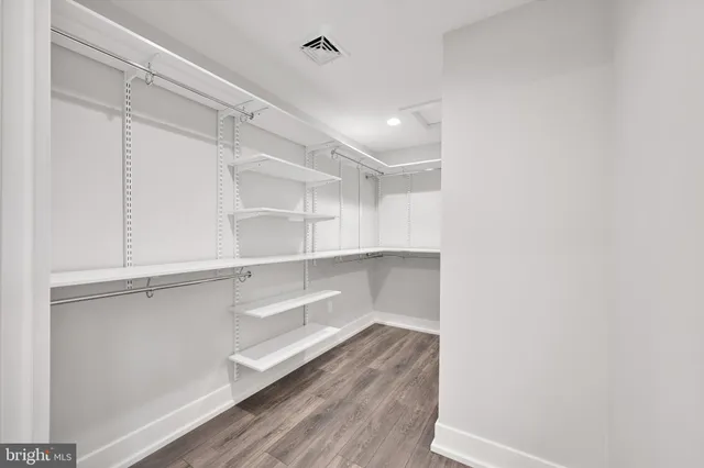 an empty room with wooden floor ceiling fan and windows
