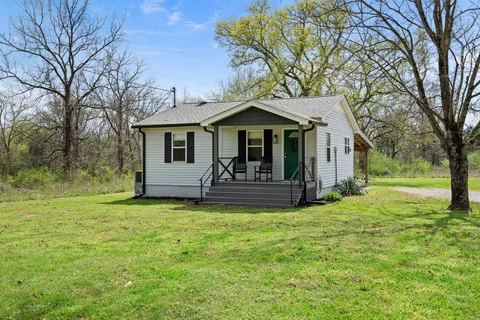 a view of a house with a yard and large tree
