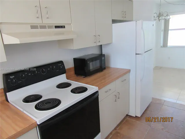 a kitchen with a refrigerator and white cabinets