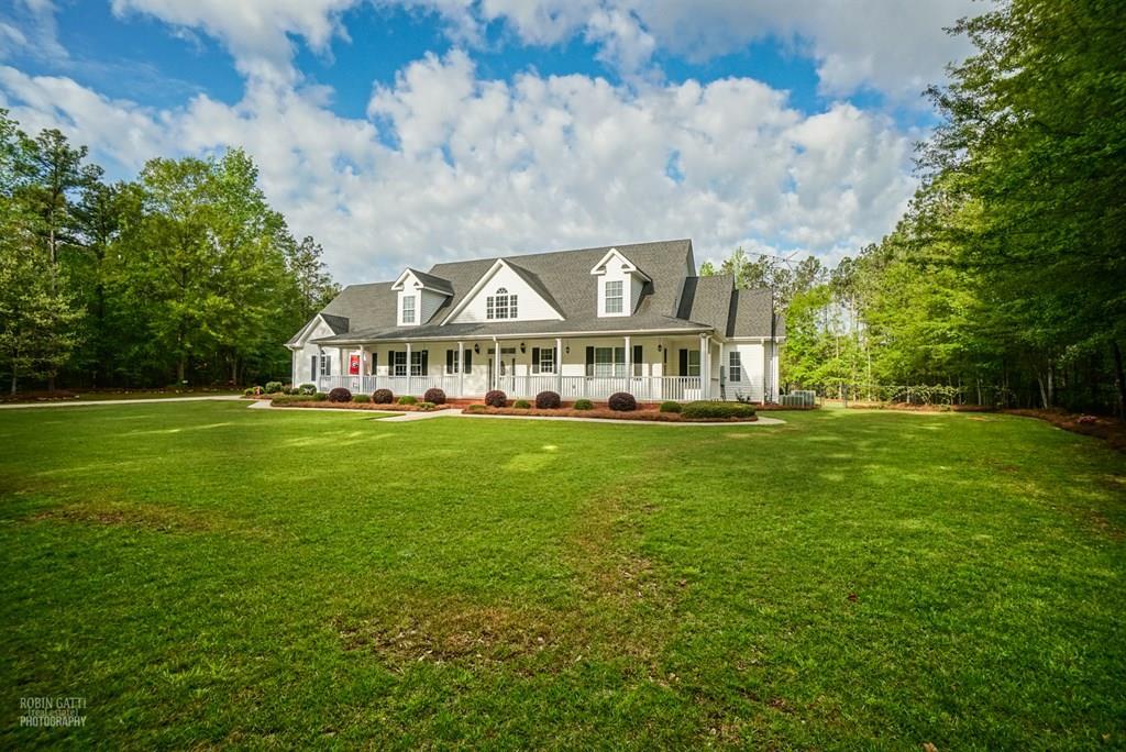 a view of a white house with a big yard and large trees