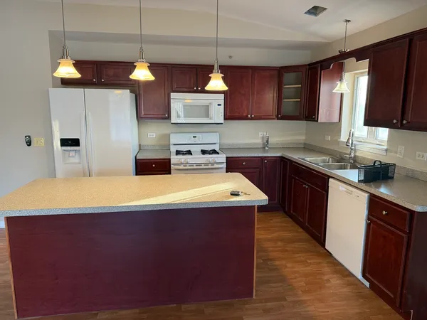 a kitchen with kitchen island granite countertop wooden cabinets stainless steel appliances a sink and a window