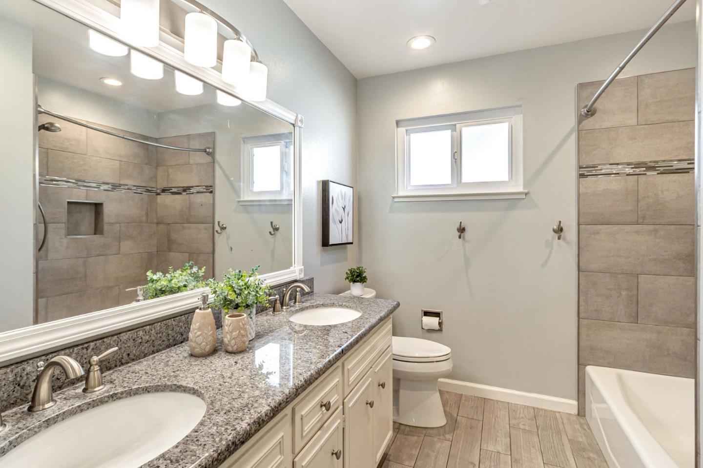 824 Buchser Way San Jose, CA 95125 - Photo 32 of 50 a bathroom with a granite countertop sink toilet a large mirror a shower and vanity