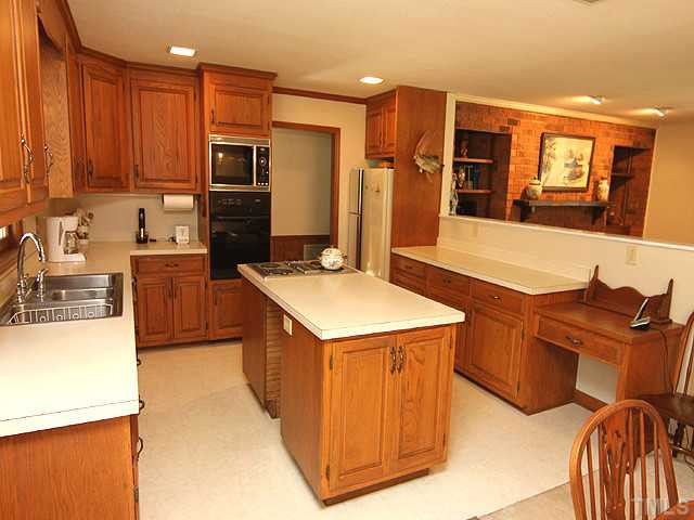 4105 Fiesta Road Durham, NC 27703 - Photo 12 of 25 a kitchen with stainless steel appliances granite countertop a stove top oven a sink a refrigerator and white cabinets with wooden floor