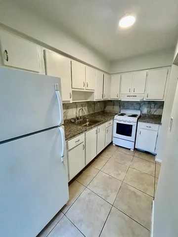 a kitchen with granite countertop a refrigerator and a sink