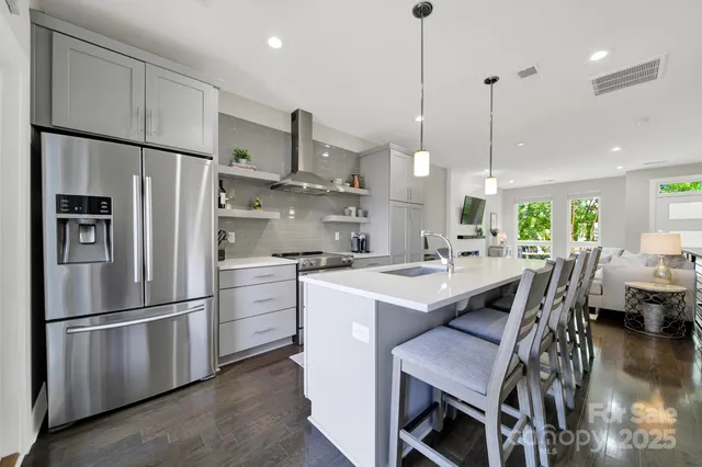 a kitchen with stainless steel appliances a refrigerator a sink a stove a table and chairs
