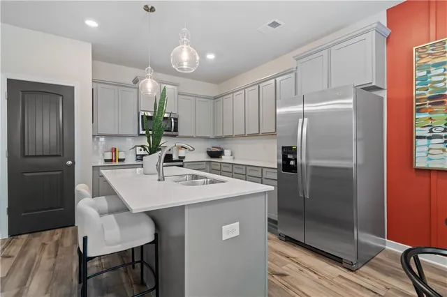 a kitchen with stainless steel appliances a refrigerator a sink a stove a dining table and chairs