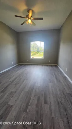 an empty room with a window and a ceiling fan