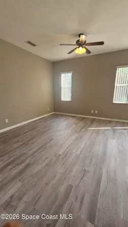 a view of an empty room with wooden floor and window
