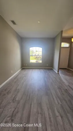 an empty room with wooden floor and windows