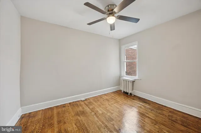 an empty room with a window and ceiling fan