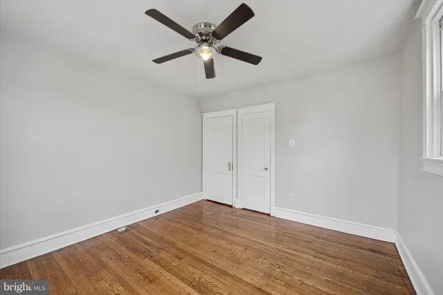 an empty room with wooden floor and ceiling fan