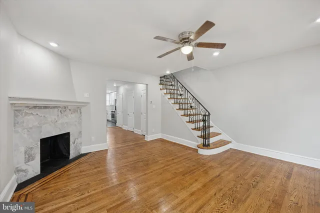 a view of an empty room wooden floor staircase and a fireplace