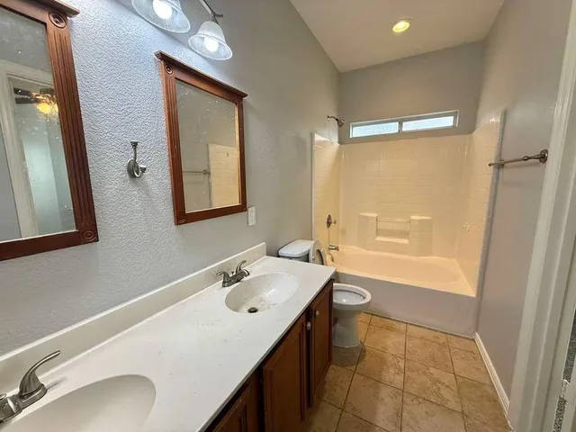a bathroom with a sink vanity granite tub and a mirror