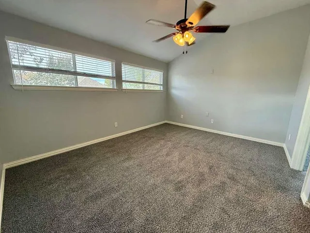 an empty room with windows and fan