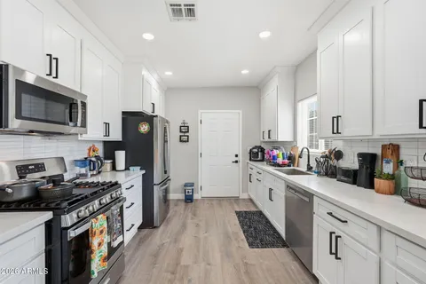 a large kitchen with stainless steel appliances granite countertop a stove a sink dishwasher and a refrigerator with wooden floor
