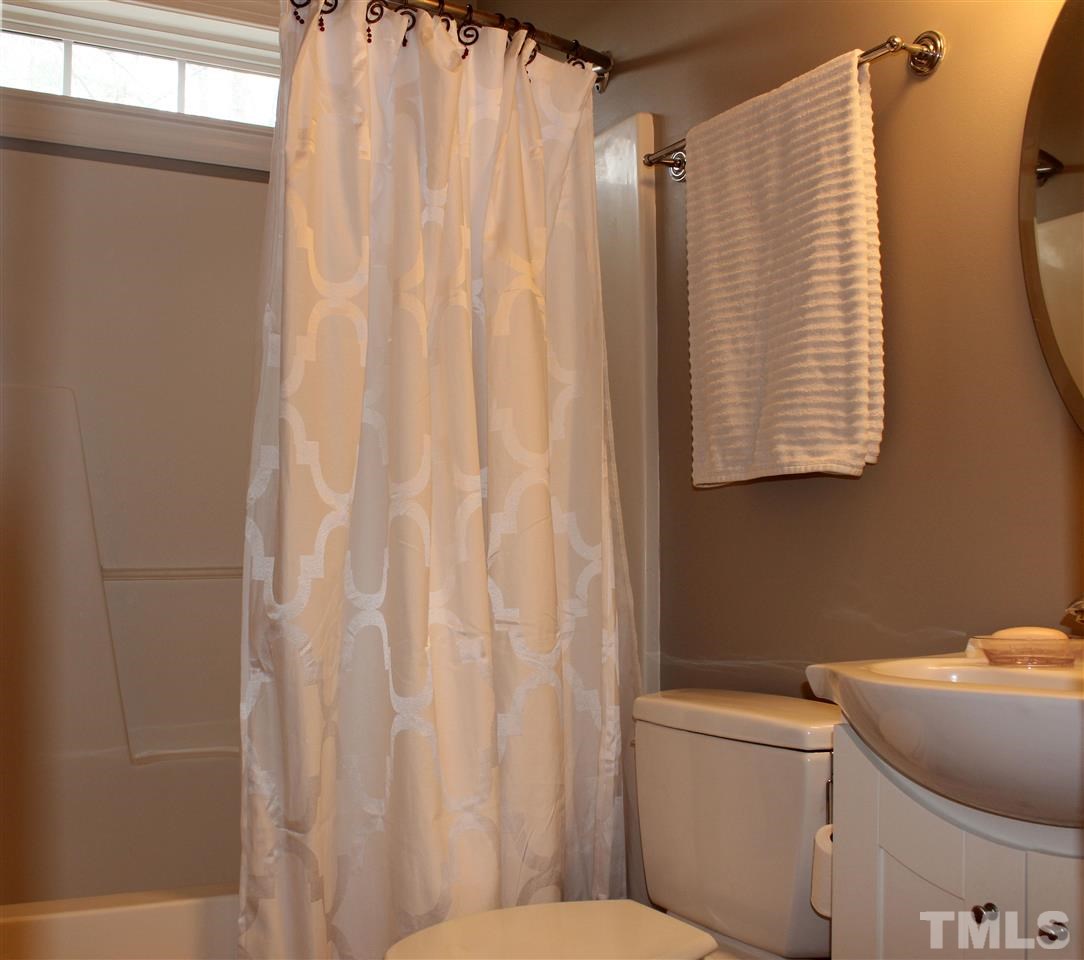 6904 Field Hill Road Raleigh, NC 27603 - Photo 18 of 25 a bathroom with a toilet and a shower curtain