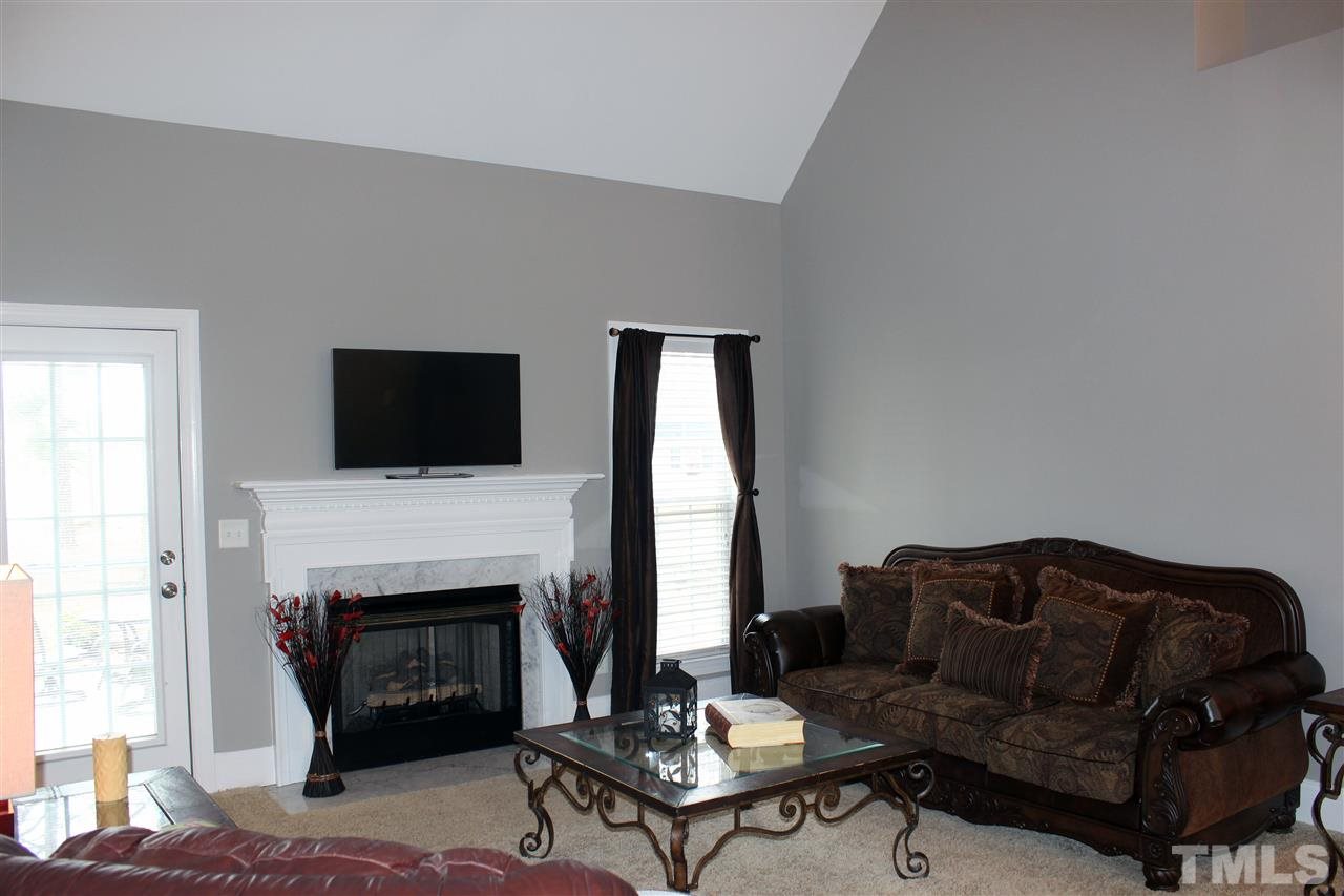 6904 Field Hill Road Raleigh, NC 27603 - Photo 6 of 25 a living room with furniture a flat screen tv and a fireplace